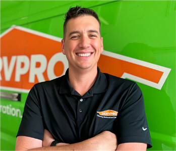 Male employee wearing a black SERVPRO shirt in front of a white wall