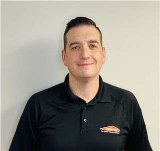 Male employee wearing a black SERVPRO shirt in front of a white wall