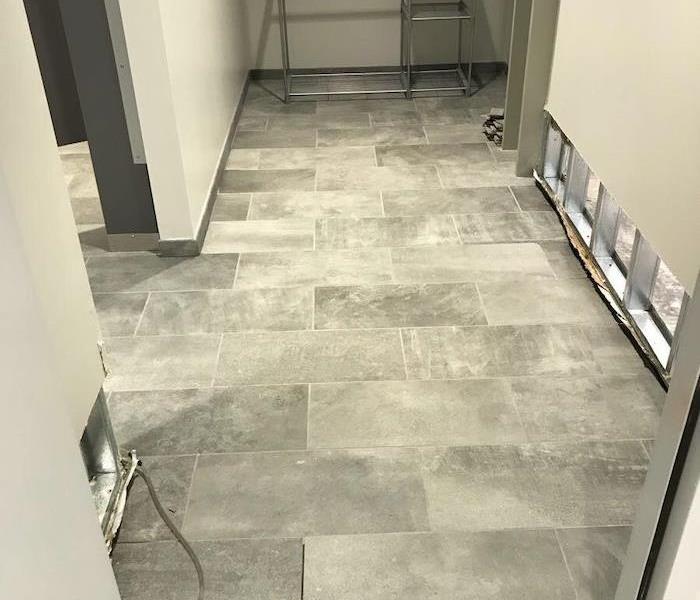 Gray tile floor in a bathroom with flood cut sheetrock
