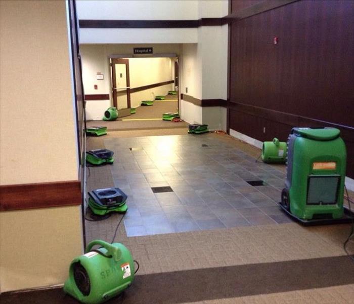 A commercial building with SERVPRO equipment on the ground.